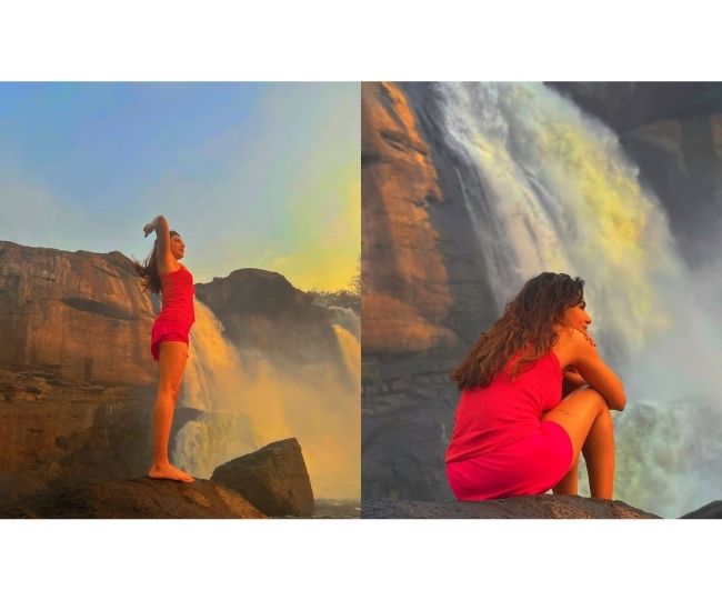 Woman practising yoga at waterfall, triangle pose stock photo