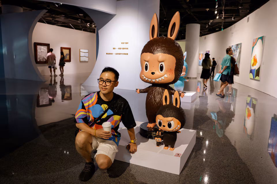  A man poses for pictures next to a life-sized Labubu figurine displayed before an auction in Beijing