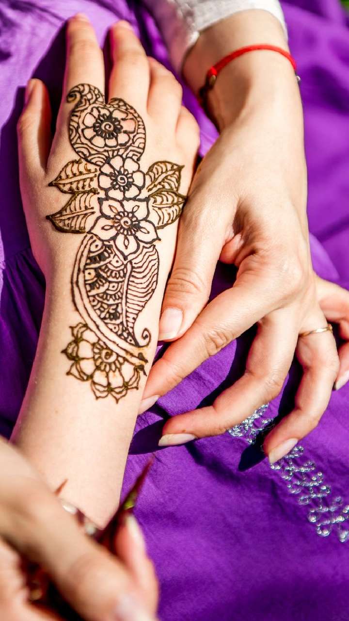 Carefully painted intricate design using henna, Mehndi art, on the hand of  young Indian woman before a Vivaah-Indian Wedding. Background bokeh of  wedding sari. Focus on hand. Stock Photo | Adobe Stock