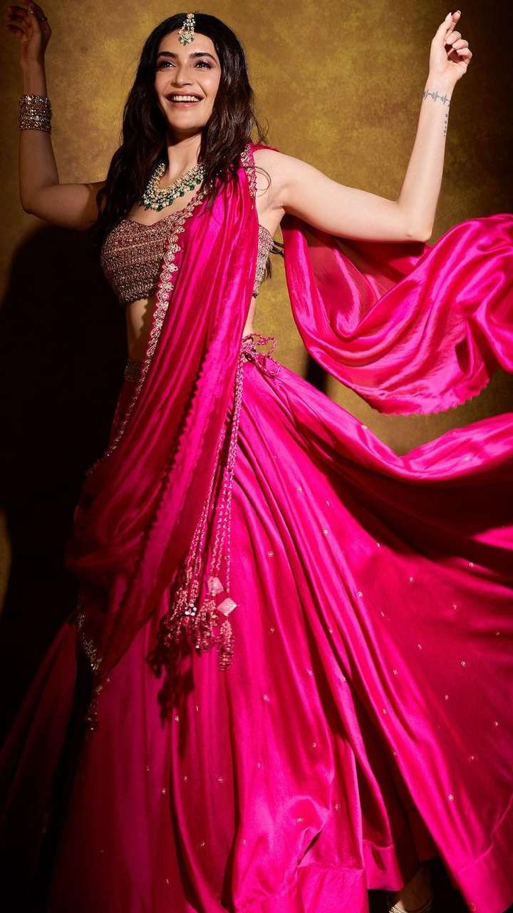 Photo of Bride looking out of window in pink lehenga with green jewellery